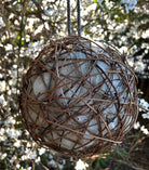 Natural sheep's wool nesting ball 20cm with dark woven willow hanging in a tree