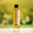 TranQuillina Calendula Body Oil bottle against a softly blurred green garden background
