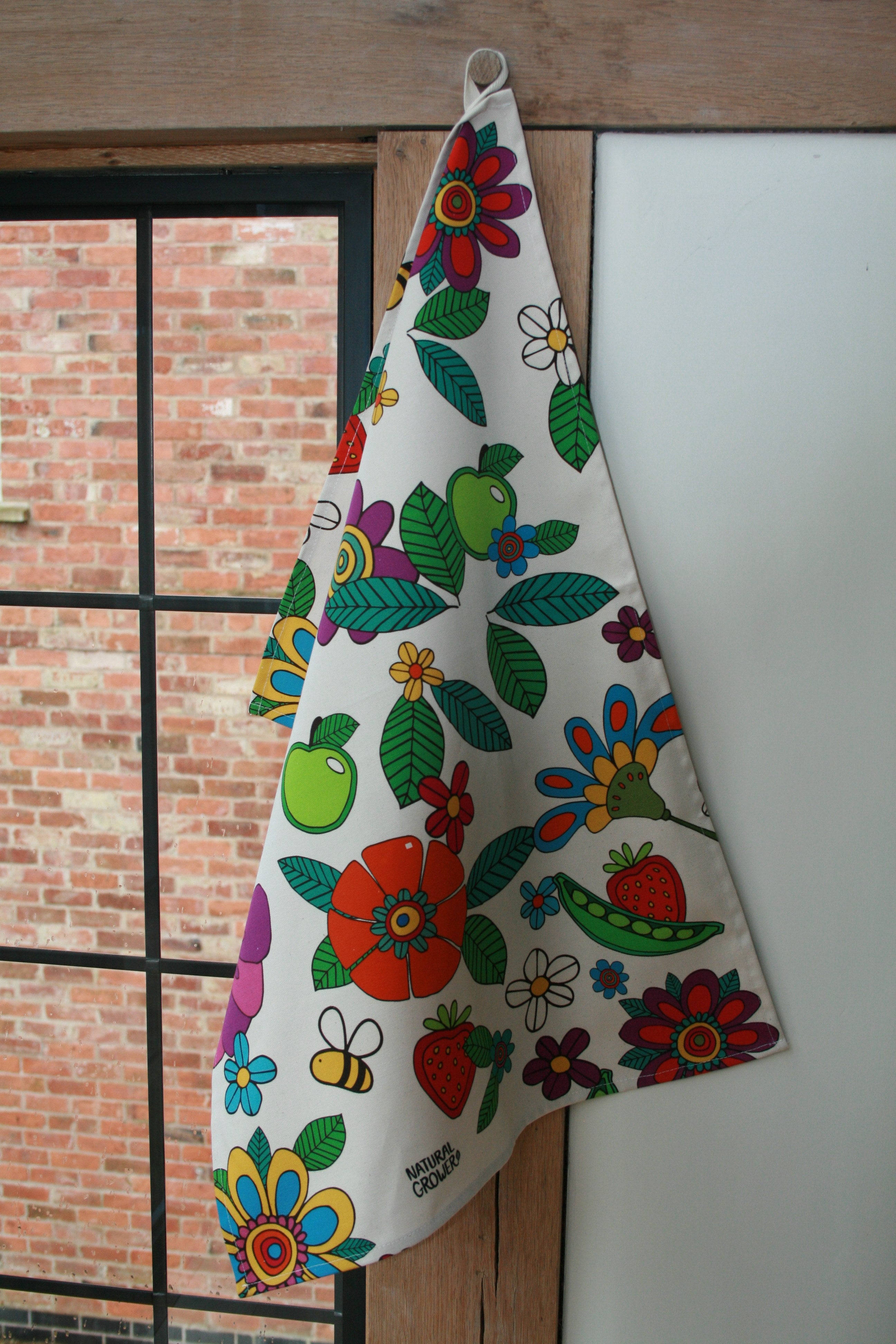 Natural Grower Flower Power organic cotton tea towel hanging in a kitchen